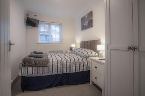 Castle Cove - 1 Bedroom Apartment - Tenby في تينبي: غرفة نوم صغيرة بها سرير ونافذة