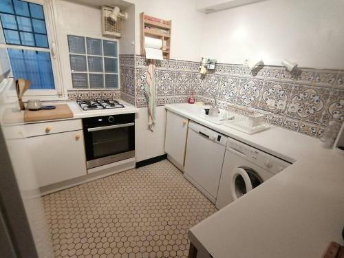 une cuisine blanche avec un lave-linge et un sèche-linge. dans l'établissement Saint-Jean de Luz,Maison de ville ancienne, face à la plage, à Sainte-Barbe