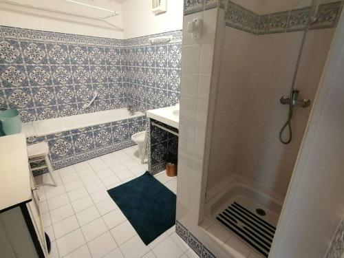 La salle de bains est pourvue d'une douche et de murs carrelés bleus et blancs. dans l'établissement Saint-Jean de Luz,Maison de ville ancienne, face à la plage, à Sainte-Barbe