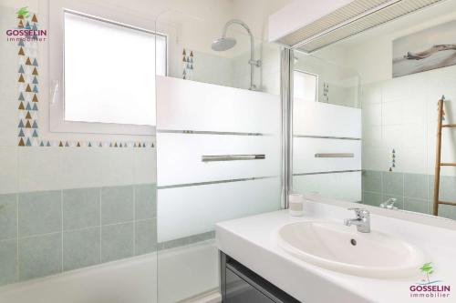 a white bathroom with a sink and a mirror at Biscarrosse Bourg Charmant appartement T3 en centre ville in Biscarrosse