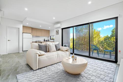 a living room with a white couch and a large window at Urban Oasis in Heart of Homebush in Sydney