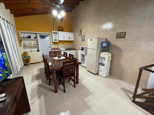 een keuken met een tafel en stoelen en een koelkast bij Asharam Asociación Argentina de Yoga in Mina Clavero