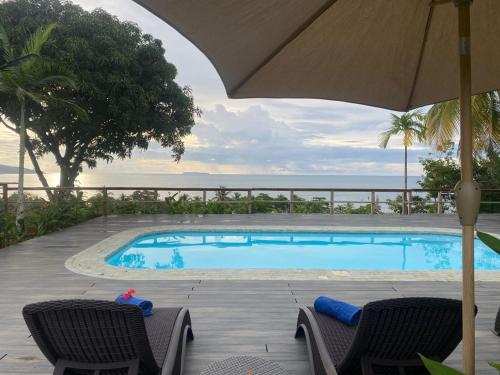 una piscina con due sedie e un ombrellone di Natural Drake Bay Hotel Boutique a Bahía Drake