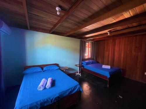 1 dormitorio con 2 camas con sábanas azules y zapatillas en Casa Nativo Spring Arenal en Fortuna