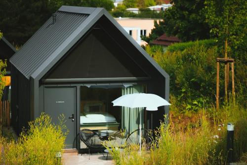 un cobertizo negro con una mesa y una sombrilla en TinyLodge 6, en Heilbad Heiligenstadt