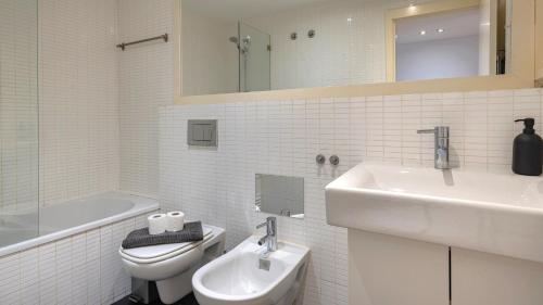 Baño blanco con lavabo y aseo en Lisbon Fancy Duplex W/ Patio by LovelyStay, en Lisboa