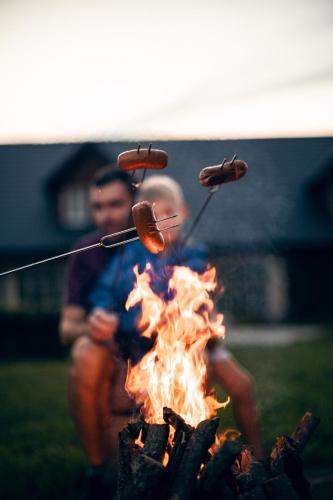 a man is roasting sausages over a fire at Penzion Pivnice - Jítravský Dvorec in Rynoltice