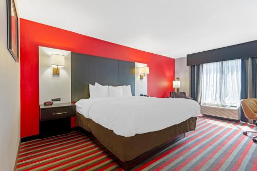 a large bed in a hotel room with a red wall at Comfort Inn & Suites Carrollton in Carrollton