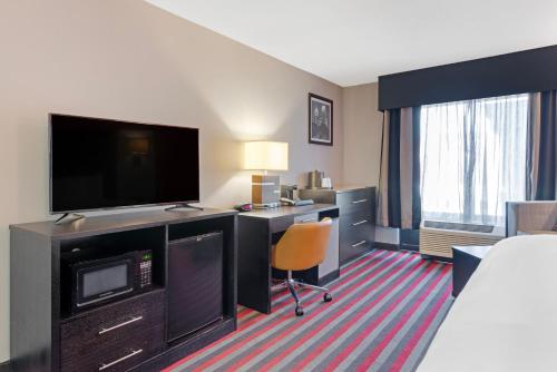 a hotel room with a bed and a desk with a television at Comfort Inn & Suites Carrollton in Carrollton