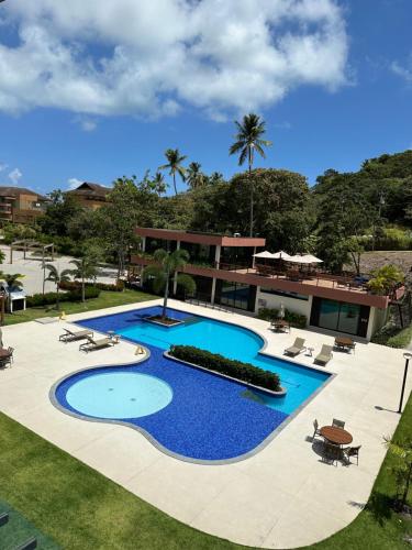 a large swimming pool with chairs and a building at Reserva dos Carneiros 301 in Tamandaré