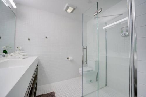 a white bathroom with a shower and a toilet at KCM Tremont Oaks Apartments 5 in Cleveland