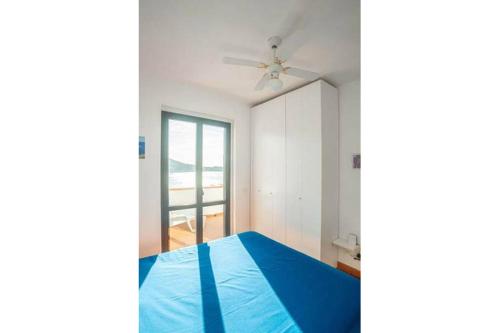 a bedroom with a blue bed and a ceiling fan at Giglio Blu 1 in Campese