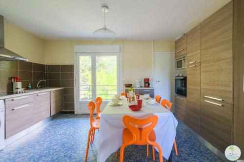une cuisine avec une table entourée de chaises orange. dans l'établissement Sanguinet Appartement 3 chambres proche du lac, à Sanguinet