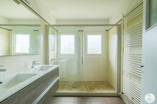 La salle de bains est pourvue d'une douche en verre et d'un lavabo. dans l'établissement Sanguinet Appartement 3 chambres proche du lac, à Sanguinet