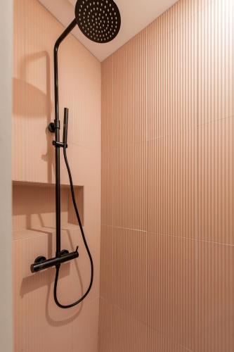 La salle de bains est pourvue d'une douche avec un pommeau de douche noir. dans l'établissement The New Suites, Paris Centre, à Paris