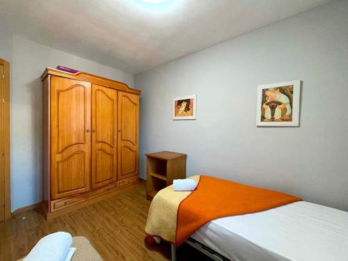 1 dormitorio con 1 cama y armario de madera en Apartamentos Candanchu 3000, en Candanchú