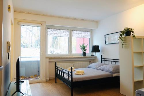 um pequeno quarto com uma cama e 2 janelas em Kompaktes Apartment in ruhiger Lage em Wolfsburg