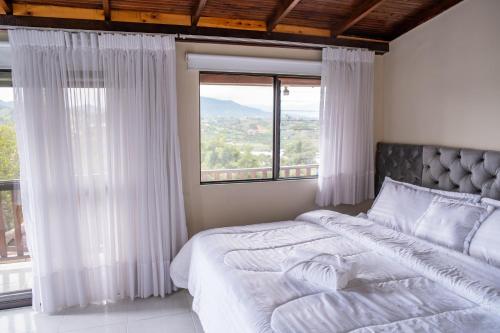 - une chambre avec un grand lit et de grandes fenêtres dans l'établissement Finca Villa Isanella, Santuario, Antioquia, à Santuario