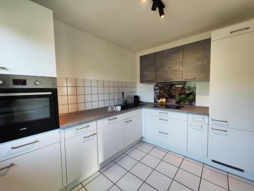 uma cozinha com armários brancos e um micro-ondas preto em Ferienwohnung nähe Montabaur A3 