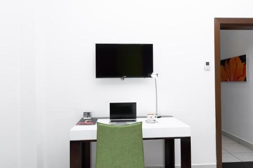 a white desk with a laptop and a tv on a wall at Ibis Styles Accra Airport in Accra