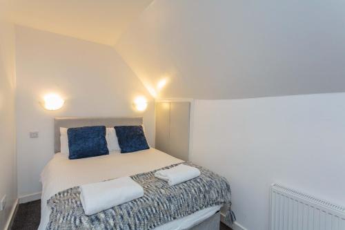 Dormitorio pequeño con cama con almohadas azules en Cherry Property - Blueberry Suite, en Blackpool