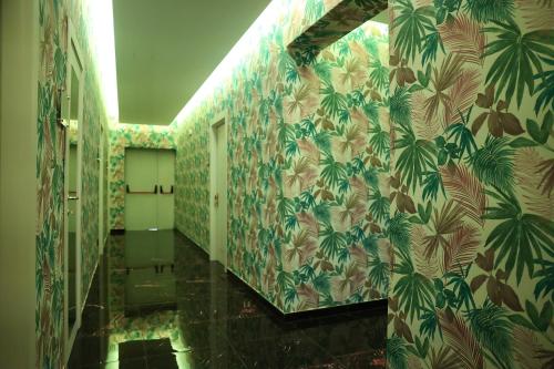 a bathroom with green and white wallpaper with palm trees at Hotel Max in Aversa