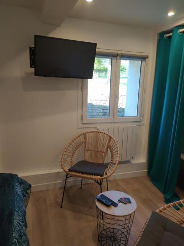 a living room with a chair and a television at CAP MANVIEUX Gîtes in Manvieux