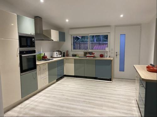 une grande cuisine avec des placards gris et une porte bleue dans l'établissement Biscarrosse Lac Maison au bord du canal pour 6 ou 7 personnes, à Biscarrosse