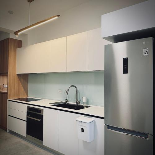 a kitchen with white cabinets and a stainless steel refrigerator at 沐正農場 木一館 嘉義包棟民宿 in Zhongpu