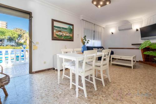 a dining room with a white table and chairs at Chalet a pie de playa in Punta Umbría