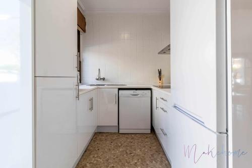 a white kitchen with a refrigerator and a dishwasher at Chalet a pie de playa in Punta Umbría