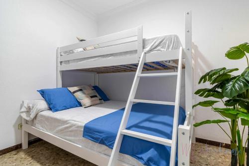 a white bunk bed with blue pillows and a ladder at Chalet a pie de playa in Punta Umbría