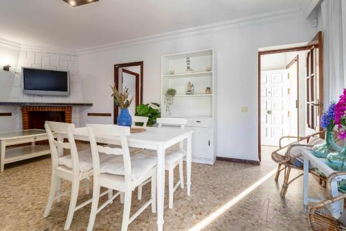 a white dining room with a white table and chairs at Chalet a pie de playa in Punta Umbría