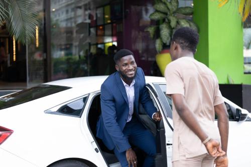 a man getting out of a white car at Ibis Styles Accra Airport in Accra