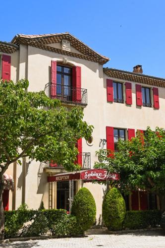 a large building with red shuttered windows and trees at Cit'Hotel Sphinx - Hotel in Montélimar
