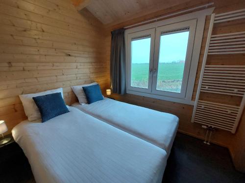 een slaapkamer met 2 bedden en een raam bij Vakantiehuisje vlakbij Leeuwarden, Swichumer Pleats in Swichum
