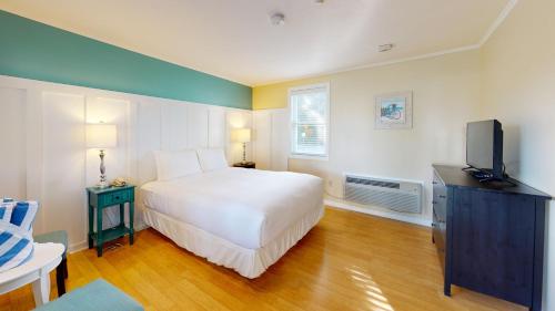a bedroom with a white bed and a tv at Breezeway Boutique Hotel in Westerly