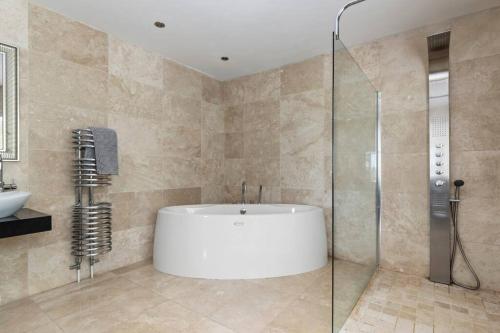 y baño con bañera y ducha acristalada. en Stunning Property Seaviews, Private Pool & Parking, en Saundersfoot
