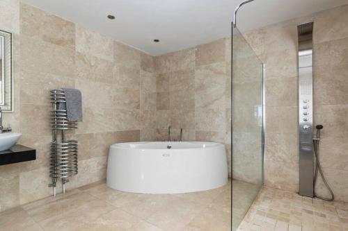 a bathroom with a tub and a glass shower at Stunning Property Seaviews, Private Pool & Parking in Saundersfoot