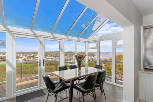 a dining room with a table and chairs and windows at Stunning Property Seaviews, Private Pool & Parking in Saundersfoot