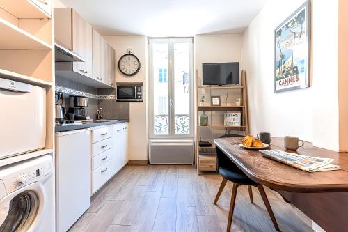 a kitchen with a table and a clock on the wall at FRGK " Charming Studio in Historic Center of Cannes" in Cannes