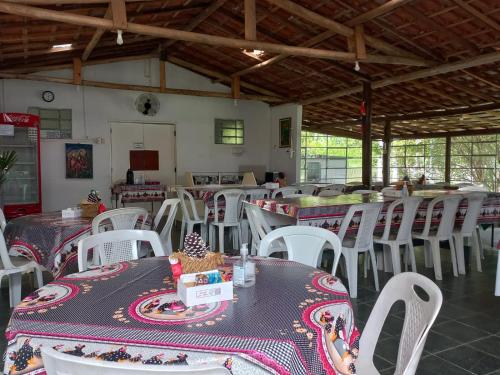 a dining room with tables and white chairs at Comunidade Anuncia-Me in Guaratinguetá