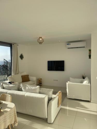 a living room with white couches and a flat screen tv at Ocean View Santa Filomena in Mindelo