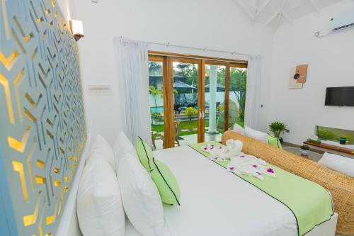 a bedroom with a white bed and a large window at The Dahlia Residence in Bentota