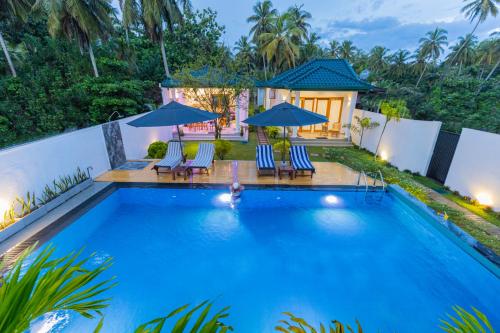 a swimming pool with blue chairs and umbrellas at The Dahlia Residence in Bentota
