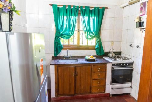 a kitchen with a sink and a stove and a window at La Casita de Gesell in Villa Gesell