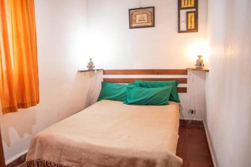 a small bedroom with a bed with green pillows at La Casita de Gesell in Villa Gesell