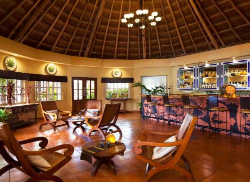 a lobby with chairs and a bar in a resort at El Dorado Seaside Suites Oceanfront, Catamarán, Ecoturistic Ranch, All & More Inclusive - Adults Only in Akumal