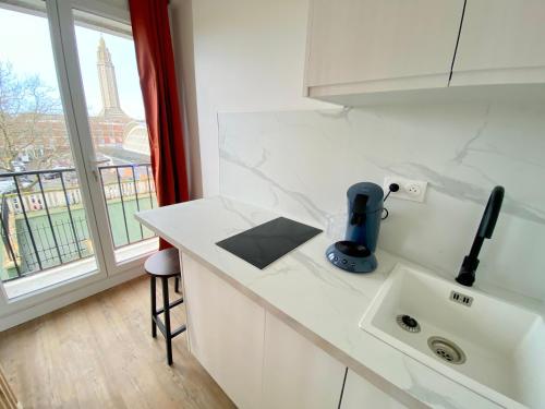 a kitchen with a sink and a window with the eiffel tower at L'Escale Appartements et Suites en bord de Mer in Le Havre