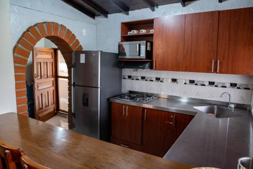 Il comprend une cuisine équipée d'un réfrigérateur en acier inoxydable et d'une table. dans l'établissement Finca Villa Isanella, Santuario, Antioquia, à Santuario